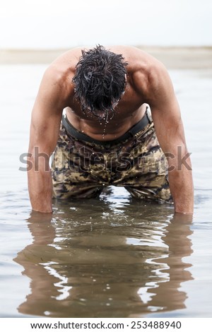 Close up Muscled Army in Camouflage Pants Kneeling on the Sea Water After Outdoor Training