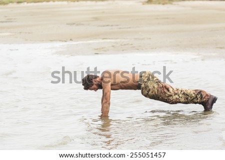 Shirtless Athletic Army in Camouflage Pants Doing Push Up Exercise at the Sea Water
