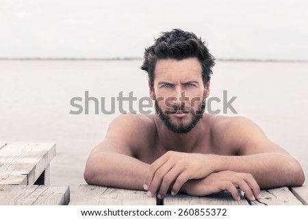Close up Portrait of Confident Gorgeous Handsome Man with No Shirt Posing at the Sea
