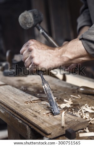 hands of carpenter with a hammer and chisel on the workbench in carpentry
