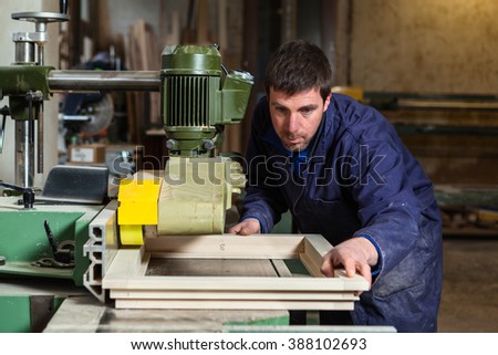 Portrait of Carpenter man cutting wooden window with table saw in Workshop