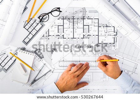 Top View of Construction plans and Male Hands drawing on blueprints; Architectural and Engineering Housing Concept.