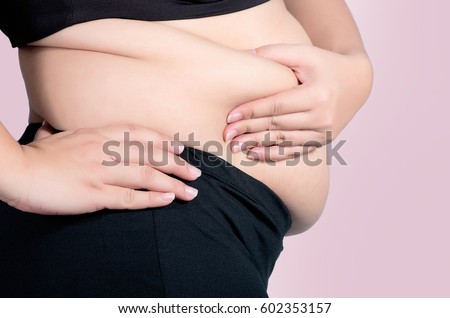 asian fat women has overweight. she used hands squeezing excess fat of the abdomen. isolated on violet background. she wants lose weight. concept of surgery and subcutaneous fat breakdown.