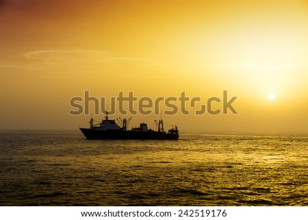 Fishing vessel for fishing in the sea. Sunset. Calm weather. Several ships.