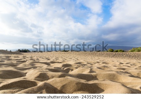 Blue sky and sand dunes with footprints. Canary islands, Maspalomas. The mountains in the background.
