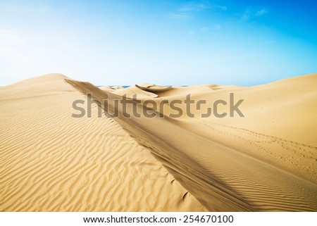 Blue sky and sand dunes with footprints. Canary islands, Maspalomas. Spain.