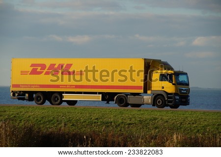 ALMERE, FLEVOLAND, THE NETHERLANDS - NOVEMBER 17, 2014: DHL delivery truck drives over a Dutch dike at dusk