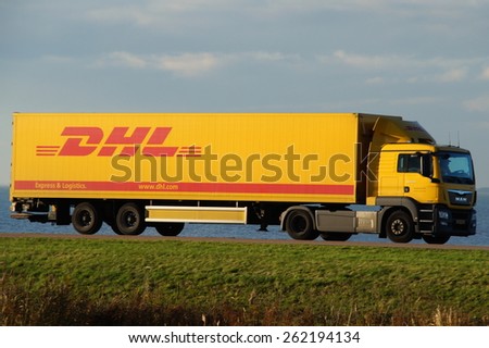 Almere Buiten, Flevoland, The Netherlands - November 17, 2014: DHL truck drives over a Dutch dike. DHL Express is a division of Deutsche Post providing international express mail services.