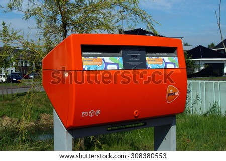 Almere Poort, Flevoland, The Netherlands - August 21, 2015: Orange PostNL mailbox standing on the side of a street in Almere . PostNL is the Dutch postal service.