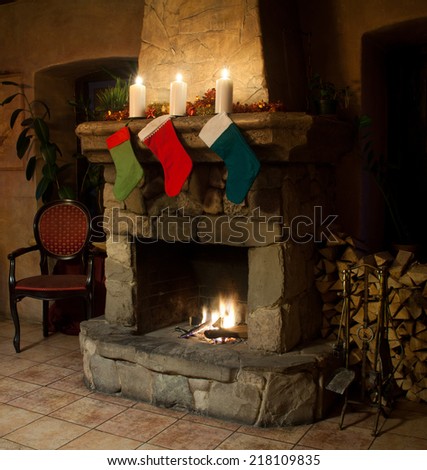 Christmas stocking on fireplace background. Chimney, candles and woodpile. Chimney place.