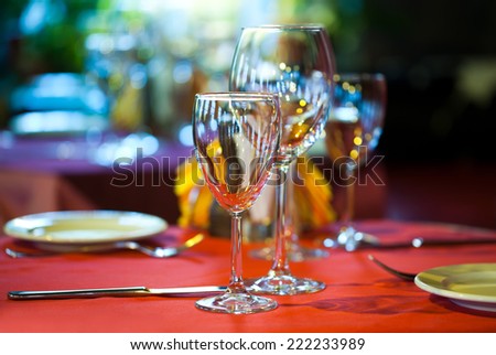 Hotel service: table in a restaurant with a red tablecloth, red napkins, wine glasses and cutlery.
