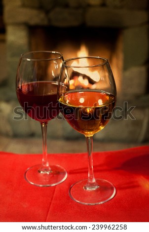 Two glasses of wine. Red tablecloth. Fireplace. Chimney. (vintage paper background, retro style).