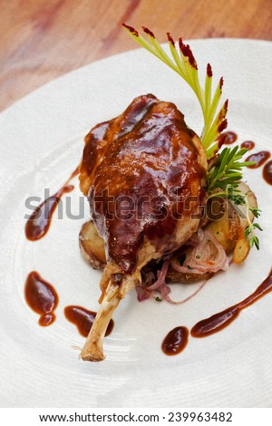 Duck pestle with potato and garlic-bacon sauce. White plate. Duck confit. Vintage paper background (toned - retro style). Roasted duck leg.