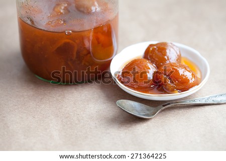 Peach, nectarine, apricot jam in a glass jar and white plate. vintage paper background. soft focus