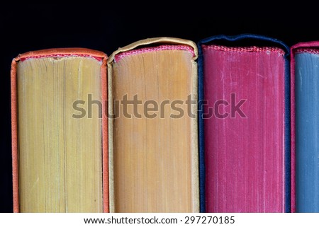 Colorful books. Yellow, violet, blue, yellow pages. Close up, textures and detailes, hard cover. Black background. Copy space. Isolated