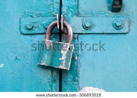 Retro metal lock on a emerald, cyan paint color door. Classic hanging lock. Soft focus.