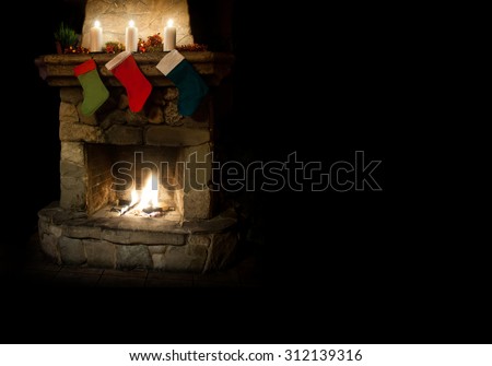 Christmas postcard template. colorful stocking on fireplace background. green, red, dark blue socks with gifts. Chimney place with candles.  Copy space, black background.