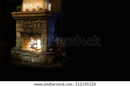 Fireplace room. Chimney place with candles and real fire and flame. Vintage style interior. Copy space, black background