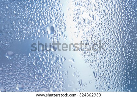 Water bubbles on the transparent blue gray glass window. Macro view water drops