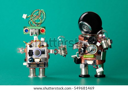 Toy robots with lamp bulbs. Circuits chip handyman characters, funny black helmet head, electric wire hairstyle colored blue red eyes. Modern steampunk heroes concept. green  background, soft focus.