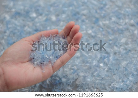 Woman hand holding Bottle flake,PET bottle flake,Plastic bottle crushed,Small pieces of cut blue plastic bottles