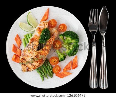 Grilled salmon steaks in white plate, isolated on black background