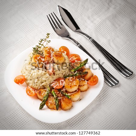 Risotto with pan seared sea scallops on table with old style vignetting
