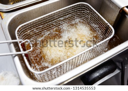 Deep frying some food in take-out restaurant kitchen, unhealty greasy food