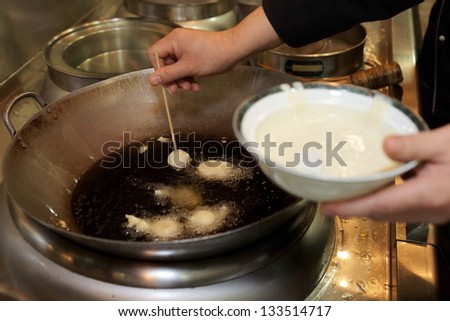 Doughnuts being fried in oil in wok pan, asian food