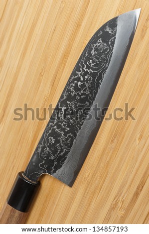 Japanese damascus carbon steel knife on wooden cutting board