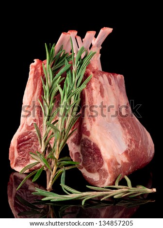 Raw rack of lamb, isolated on black background with rosemary herb
