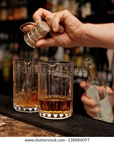 Bartender is pouring whisky in glass on the bar counter