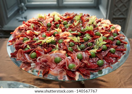 Platter with cured ham on table, catering event
