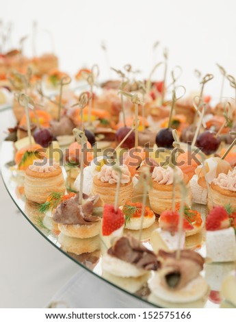 Small fish, meat and cheese snacks in plate on banquet table