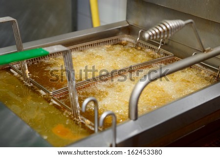 Deep fryer with boiling oil on fast food kitchen