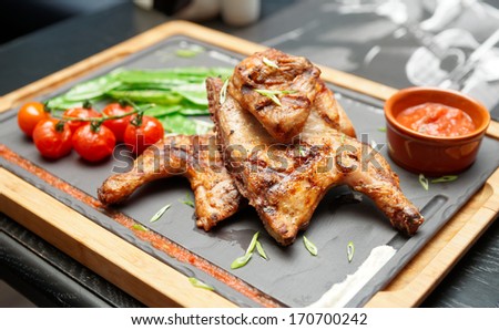 Grilled chicken with tomatoes and sauce on stone plate, British food