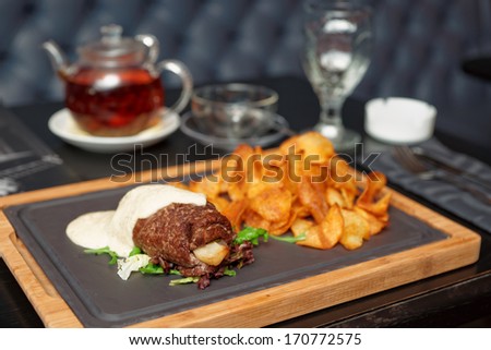 Meat rolls with white sauce and potato chips on table in an English pub