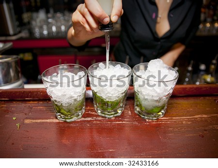 Female bartender pouring juice in glass - preparing mojito.