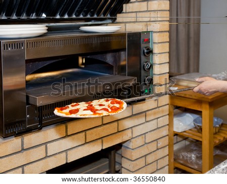Man inserting pizza in oven, restaurant kitchen