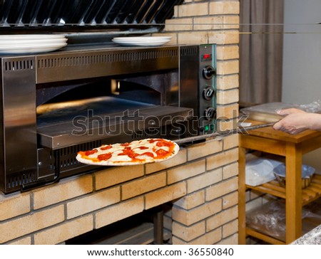 Pizza Restaurant Kitchen man inserting pizza in oven, restaurant kitchen stock photo Pizza Restaurant Kitchen man inserting pizza in oven, restaurant kitchen stock photo