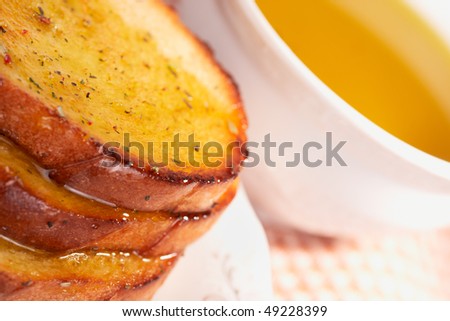 Three pieces of toasted bread in olive oil, cup of oil in background