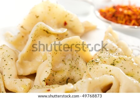 Ravioli with spicy herbs and butter, closeup, red saffron in background