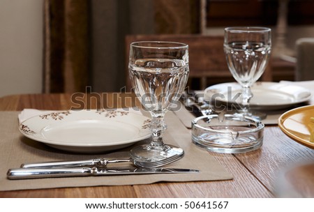 Table in a rustic cuisine restaurant, natural light, focus is on the glass