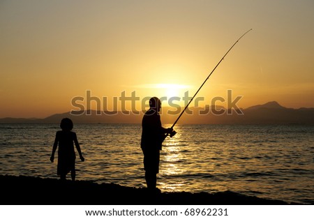 Man and a little girl fishing in the evening, Mallorca, Spain