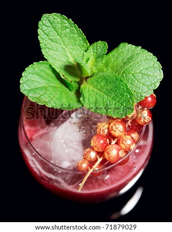 Delicious red cocktail on the rocks with mint and currant isolated on black