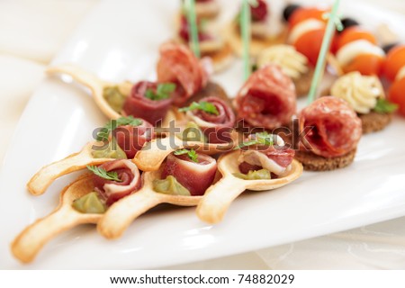 Canapes with ham tartlets on porcelain platter, selective focus
