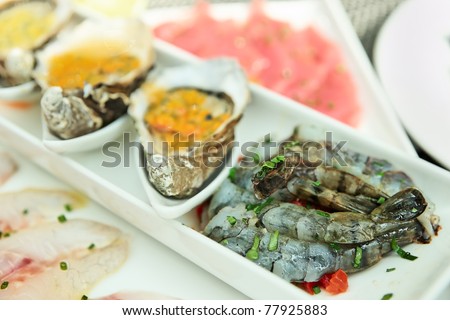 Plate with oysters, seabass, tuna and shrimps on restaurant table