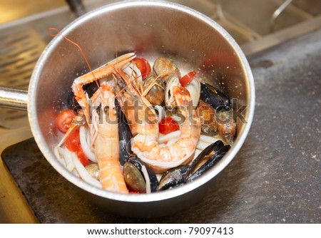 Seafood soup cooking in metal pot on commercial kitchen, copy space
