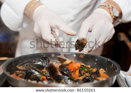 Chef frying mussels on commercial kitchen in restaurant, close-up on hands