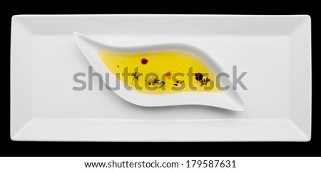 Olive oil with herbs in gravy boat, isolated on black background